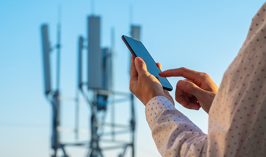 person with phone in front of 5G tower